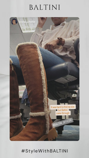 A woman is sitting in an office chair wearing a pair of stylish brown knee-high boots with white fur lining from BALTINI. She is dressed in a light-colored top and blue jeans. The image has an overlay with text mentioning the difficulty of finding the right size and a ‘BALTINI OVERKNEE’ label. The branding and hashtag ‘#StyleWithBALTINI’ are also visible at the bottom of the image.